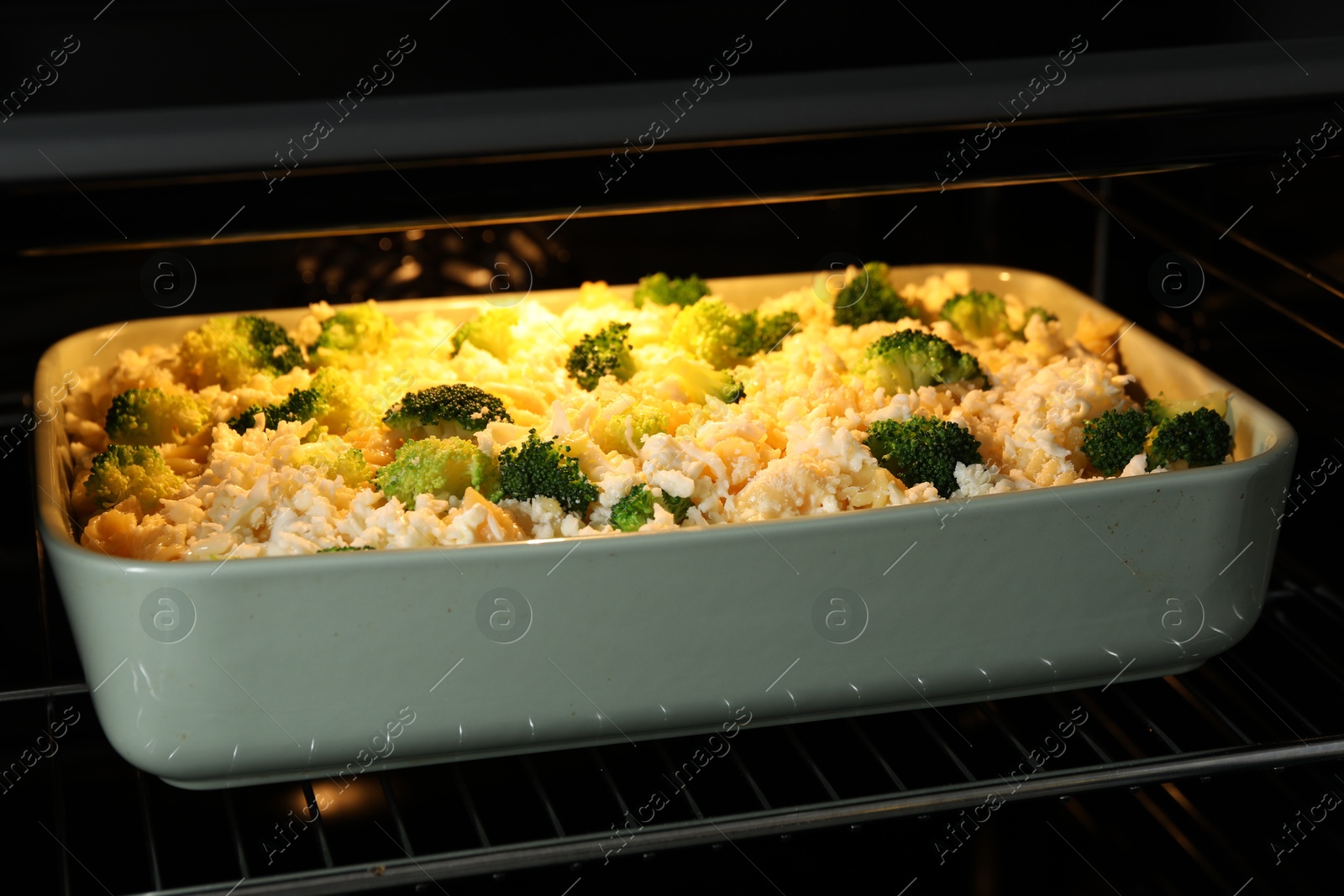 Photo of Baking dish with uncooked pasta casserole in oven, closeup