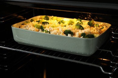 Photo of Baking dish with uncooked pasta casserole in oven, closeup