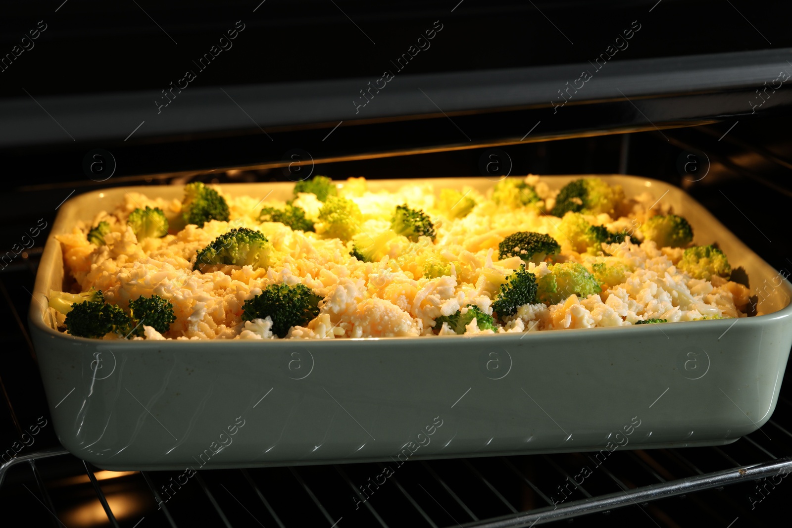 Photo of Baking dish with uncooked pasta casserole in oven, closeup