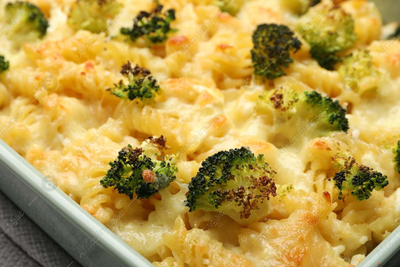 Photo of Tasty pasta casserole with cheese and broccoli in baking dish on table, closeup