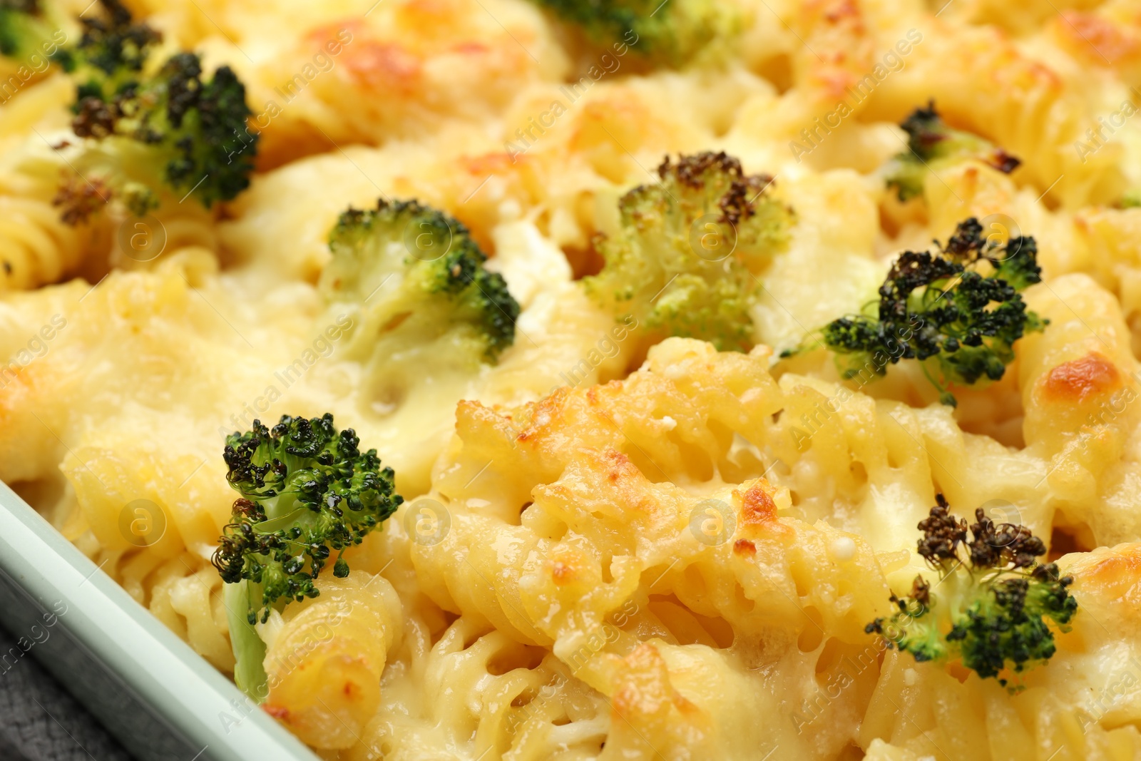 Photo of Tasty pasta casserole with cheese and broccoli in baking dish on table, closeup