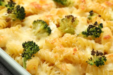 Photo of Tasty pasta casserole with cheese and broccoli in baking dish on table, closeup