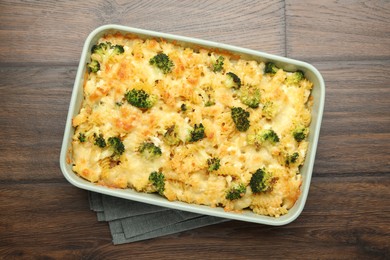 Photo of Tasty pasta casserole with cheese and broccoli in baking dish on wooden table, top view