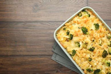 Photo of Tasty pasta casserole with cheese and broccoli in baking dish on wooden table, top view. Space for text