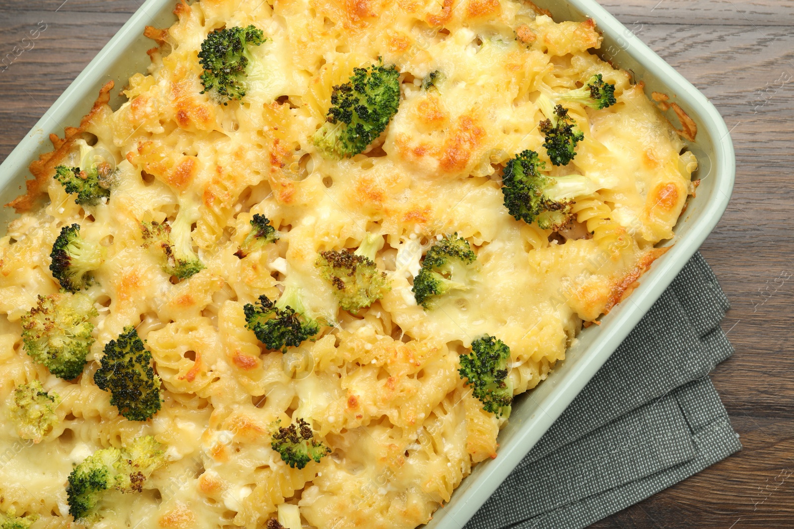 Photo of Tasty pasta casserole with cheese and broccoli in baking dish on wooden table, top view