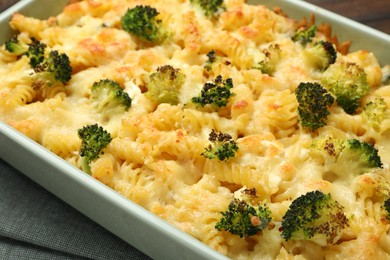 Photo of Tasty pasta casserole with cheese and broccoli in baking dish on table, closeup