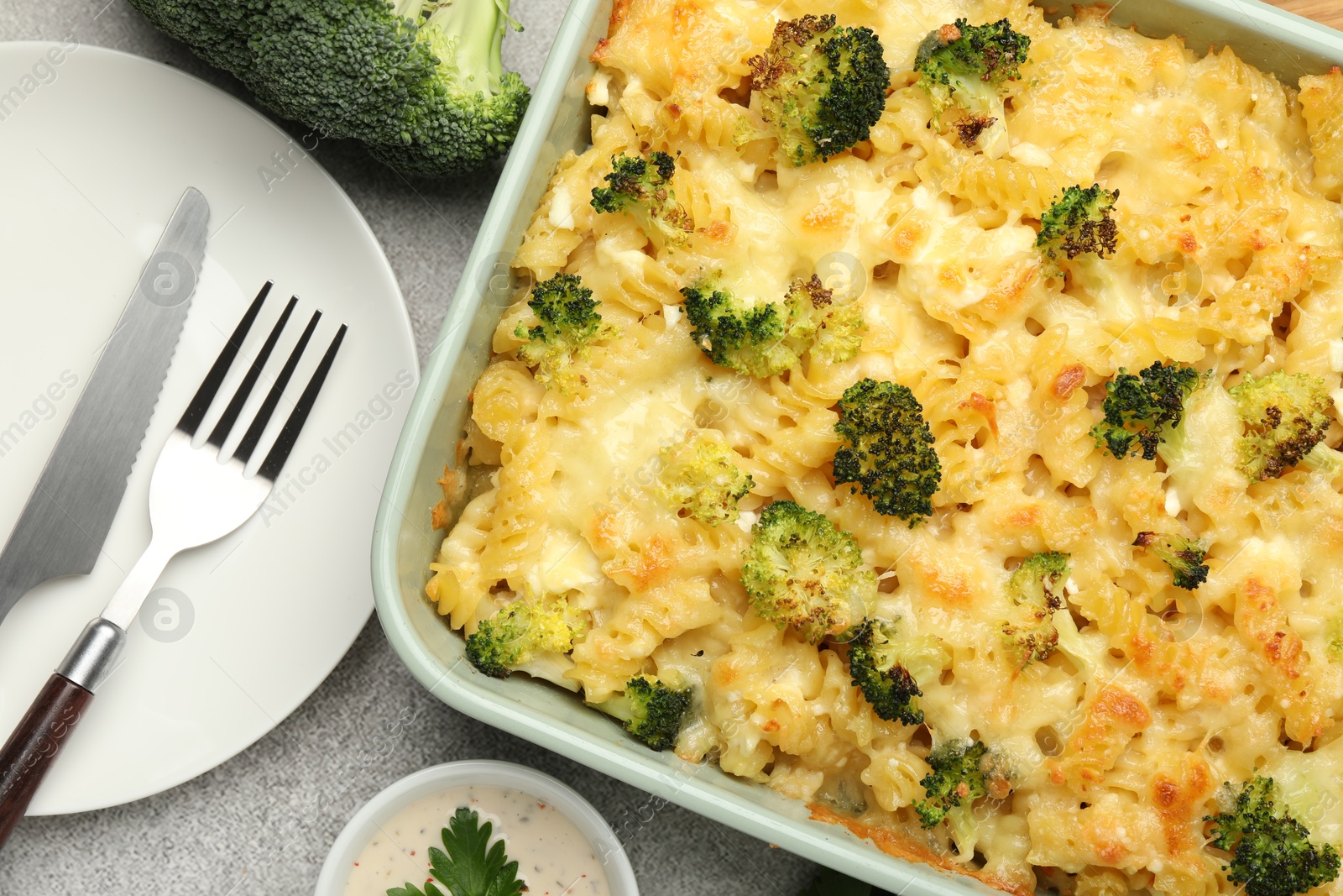 Photo of Tasty pasta casserole with cheese, broccoli and sauce on grey table, flat lay