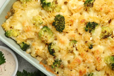 Photo of Tasty pasta casserole with cheese, broccoli and sauce on table, top view