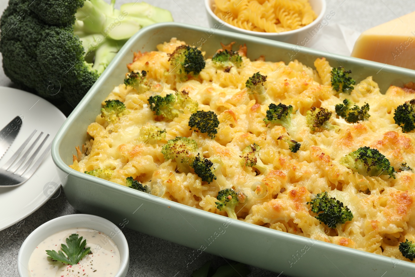 Photo of Tasty pasta casserole with cheese, broccoli and sauce on grey table, closeup