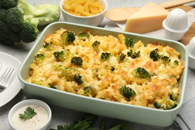 Photo of Tasty pasta casserole with cheese, broccoli and sauce on grey table, closeup