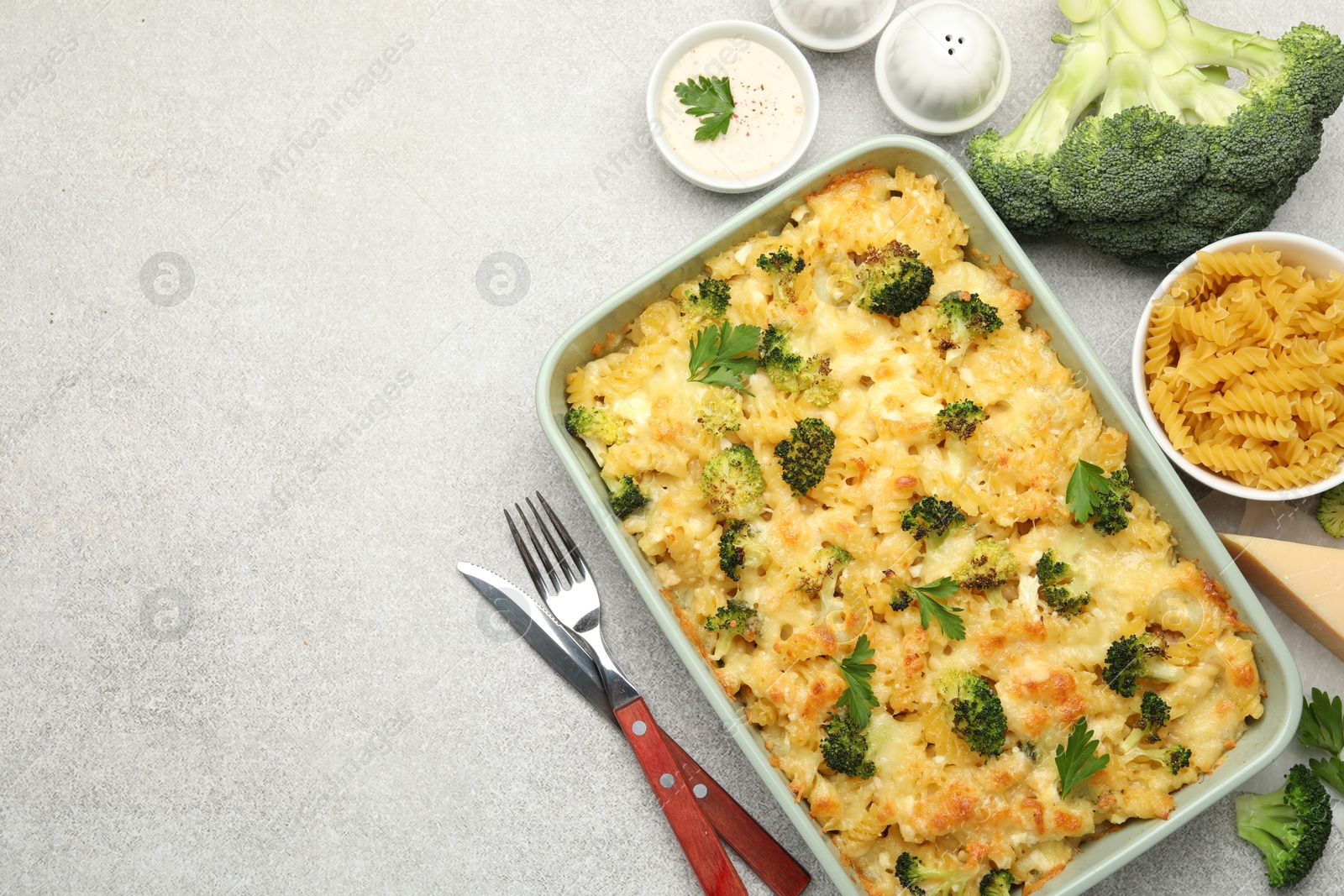 Photo of Tasty pasta casserole with cheese and broccoli served on grey table, flat lay. Space for text