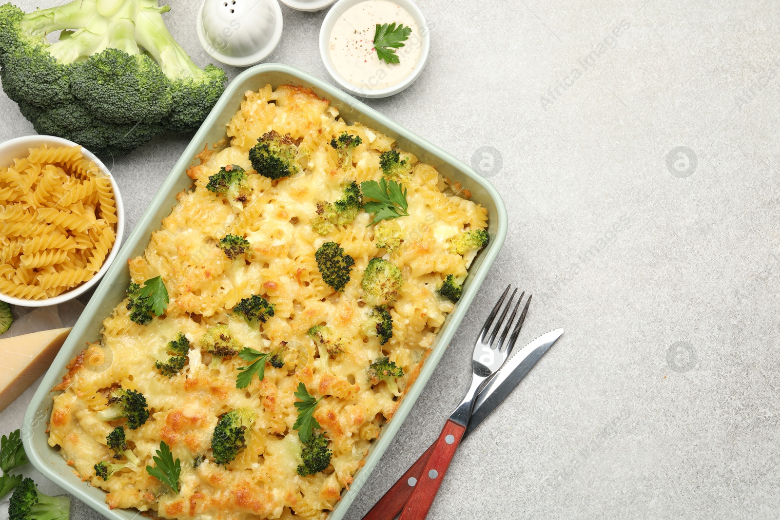 Photo of Tasty pasta casserole with cheese and broccoli served on grey table, flat lay. Space for text