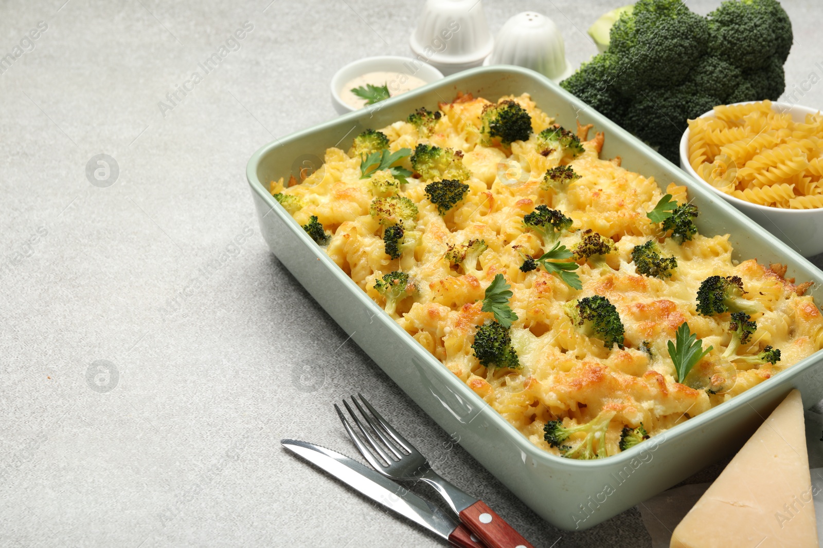 Photo of Tasty pasta casserole with cheese and broccoli served on grey table, closeup. Space for text