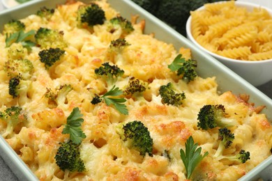 Photo of Tasty pasta casserole with cheese and broccoli in baking dish on table, closeup