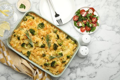 Photo of Tasty pasta casserole with cheese and broccoli served on white marble table, flat lay. Space for text