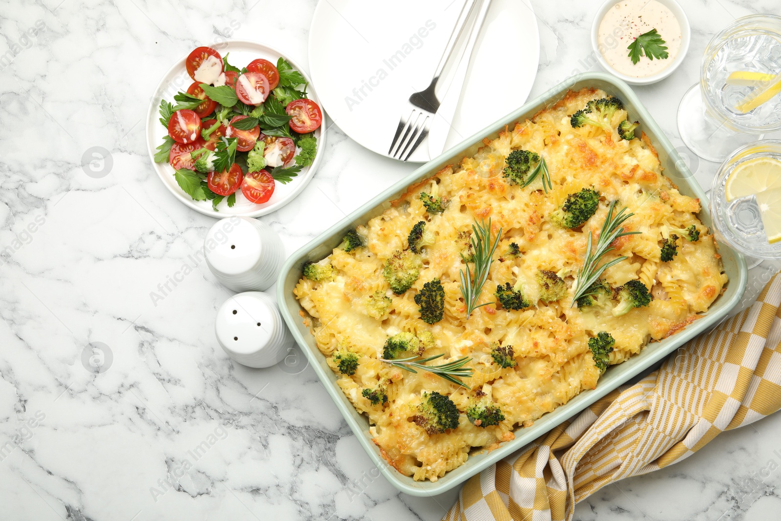 Photo of Tasty pasta casserole with cheese and broccoli served on white marble table, flat lay. Space for text