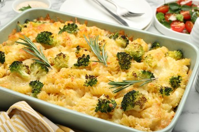 Photo of Tasty pasta casserole with cheese, rosemary and broccoli in baking dish on table, closeup