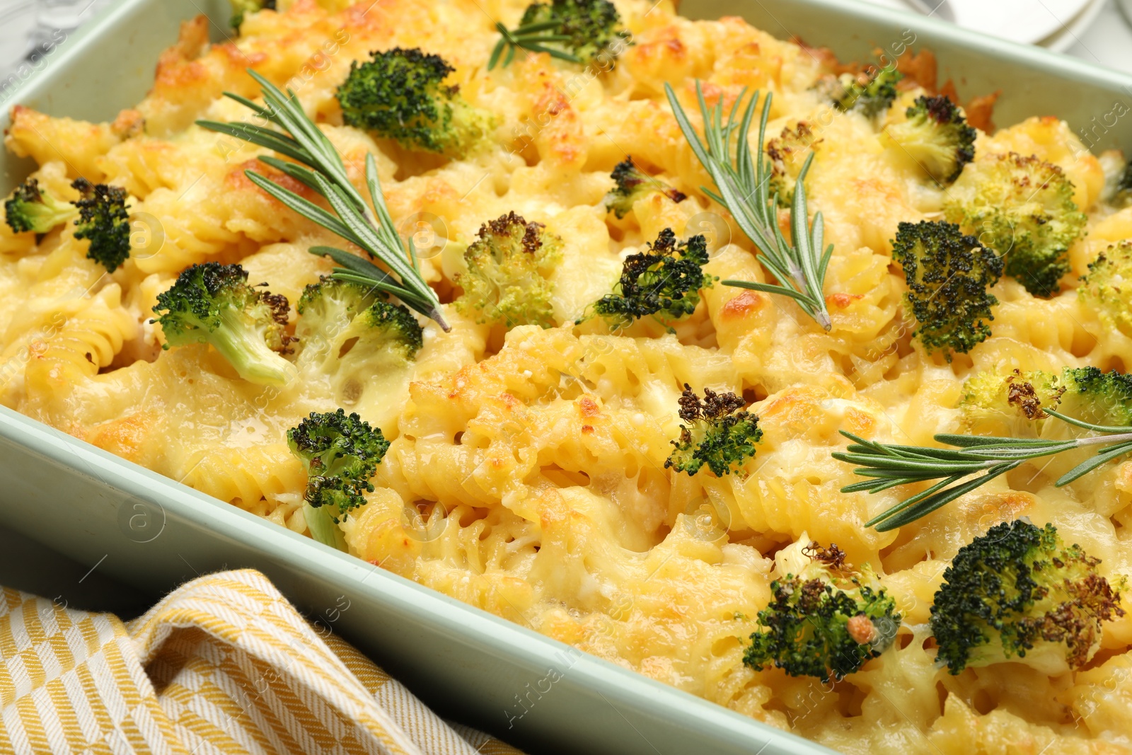 Photo of Tasty pasta casserole with cheese, rosemary and broccoli in baking dish on table, closeup