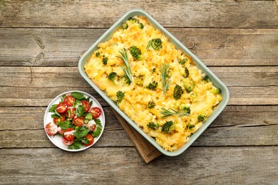 Photo of Tasty pasta casserole with cheese, rosemary, broccoli and salad on wooden table, top view