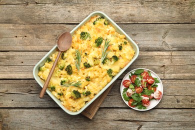 Photo of Tasty pasta casserole with cheese, rosemary, broccoli and salad on wooden table, top view