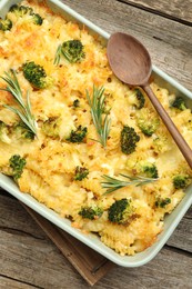 Photo of Tasty pasta casserole with cheese, rosemary and broccoli in baking dish on wooden table, top view