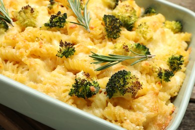 Photo of Tasty pasta casserole with cheese, rosemary and broccoli in baking dish on table, closeup