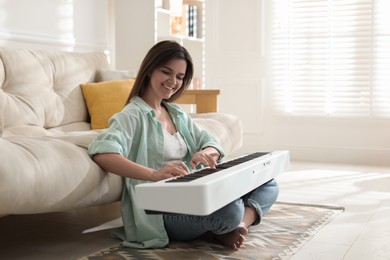 Photo of Smiling woman playing synthesizer on floor at home. Space for text