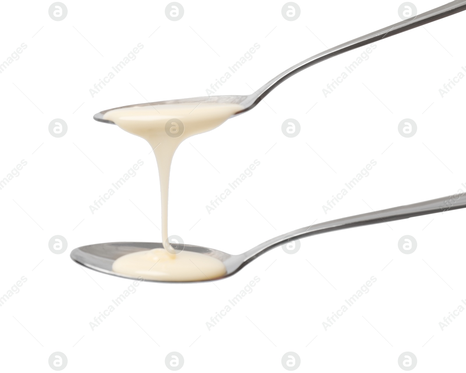 Photo of Condensed milk flowing down from spoons isolated on white