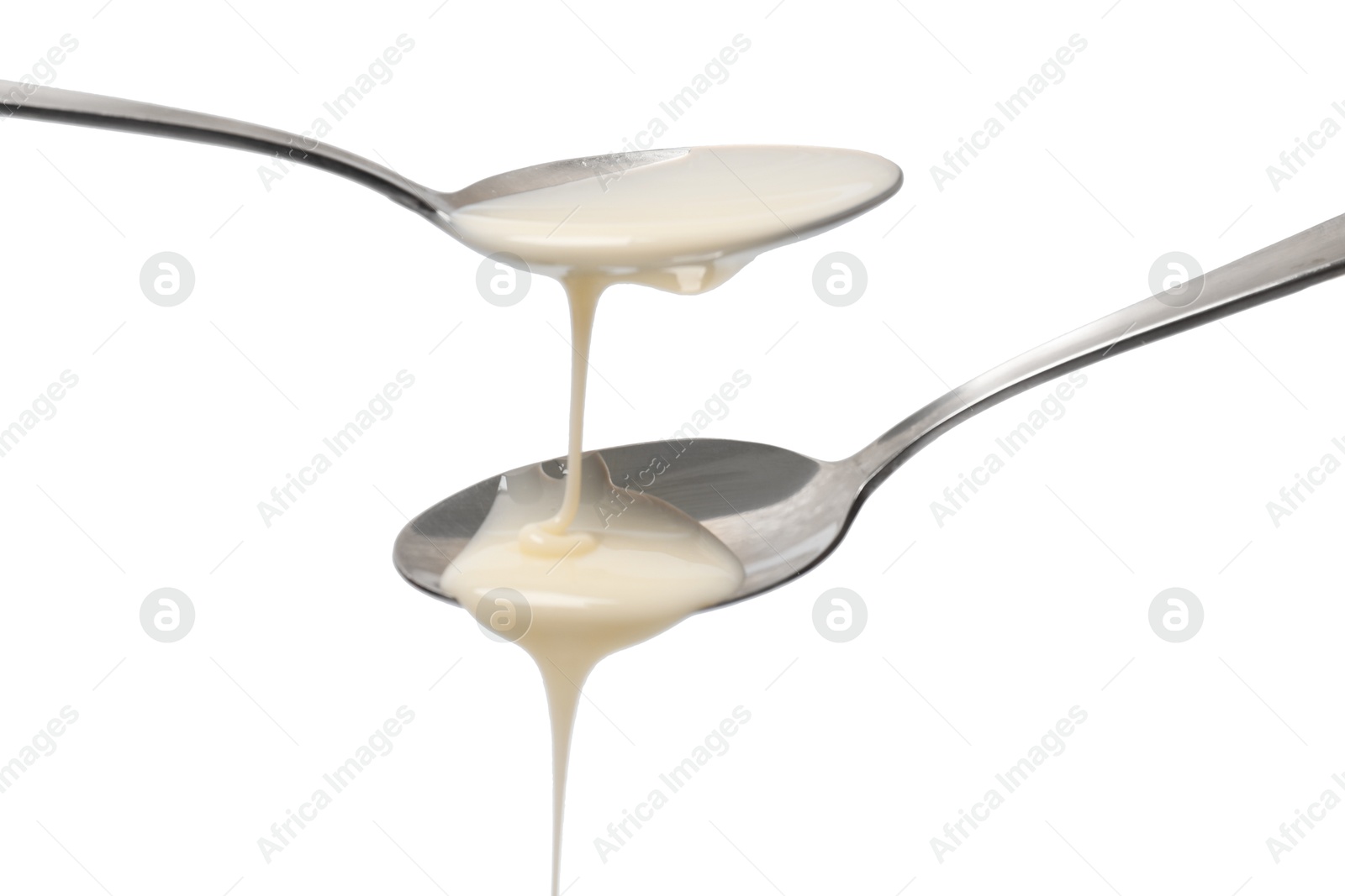 Photo of Condensed milk flowing down from spoons isolated on white