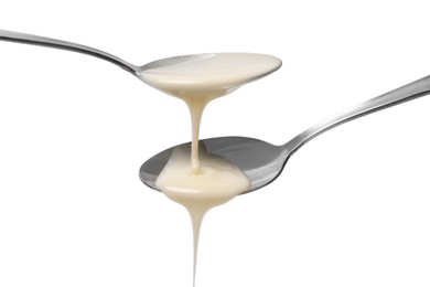 Photo of Condensed milk flowing down from spoons isolated on white