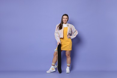 Photo of Smiling woman with skateboard on violet background