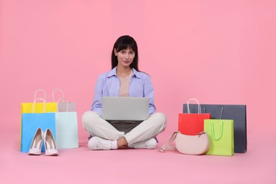 Photo of Internet shopping. Beautiful woman with laptop and colorful bags on pink background