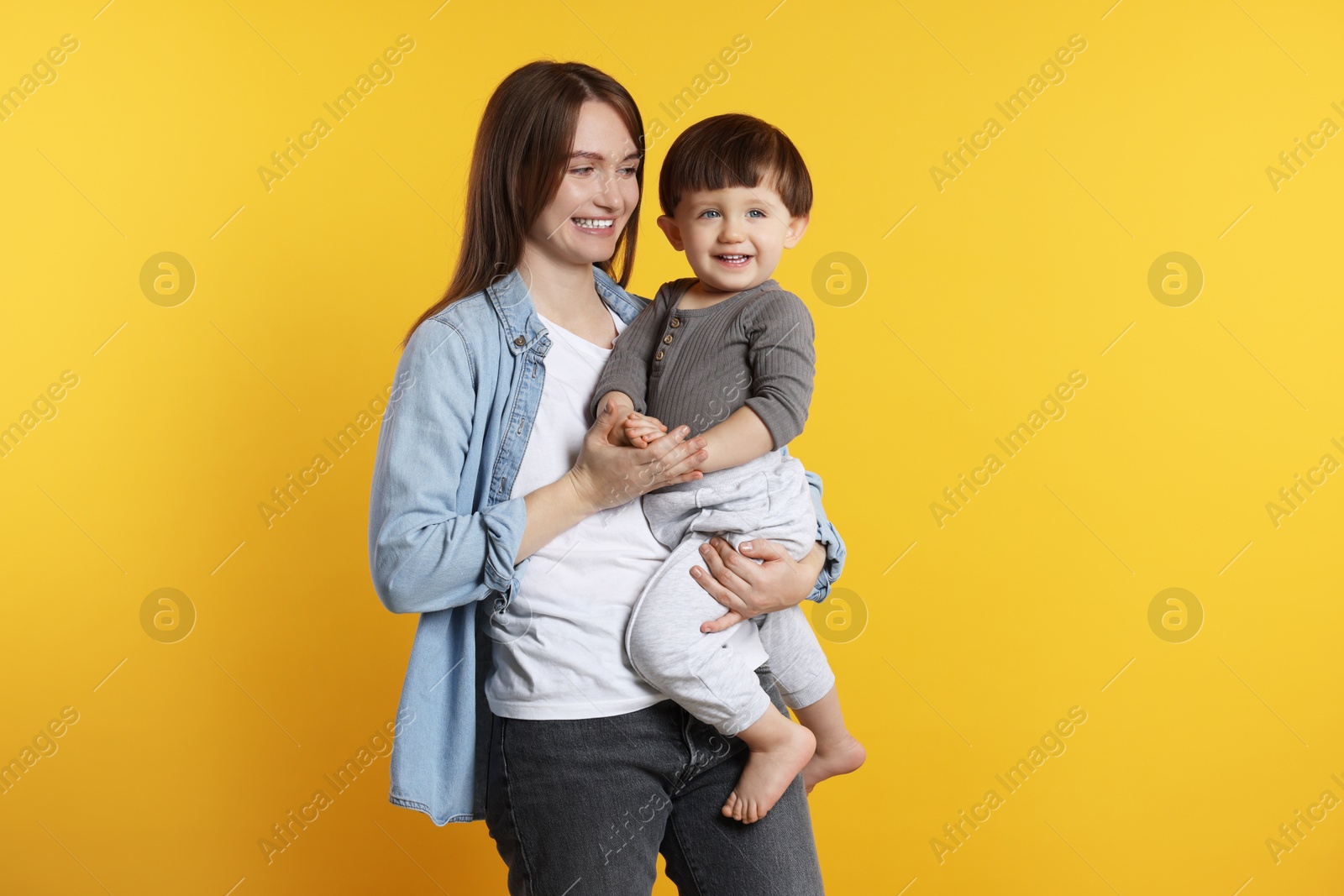 Photo of Happy mother with her cute little son on yellow background