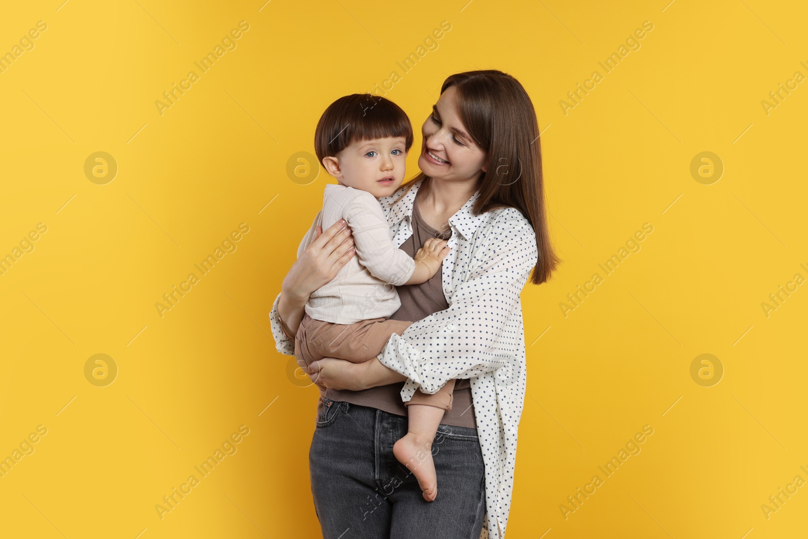 Photo of Happy mother with her cute little son on yellow background