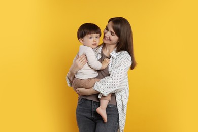 Photo of Happy mother with her cute little son on yellow background