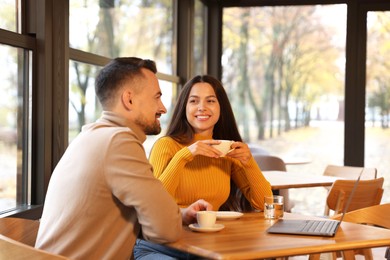 Photo of Colleagues with laptop working together at table in cafe