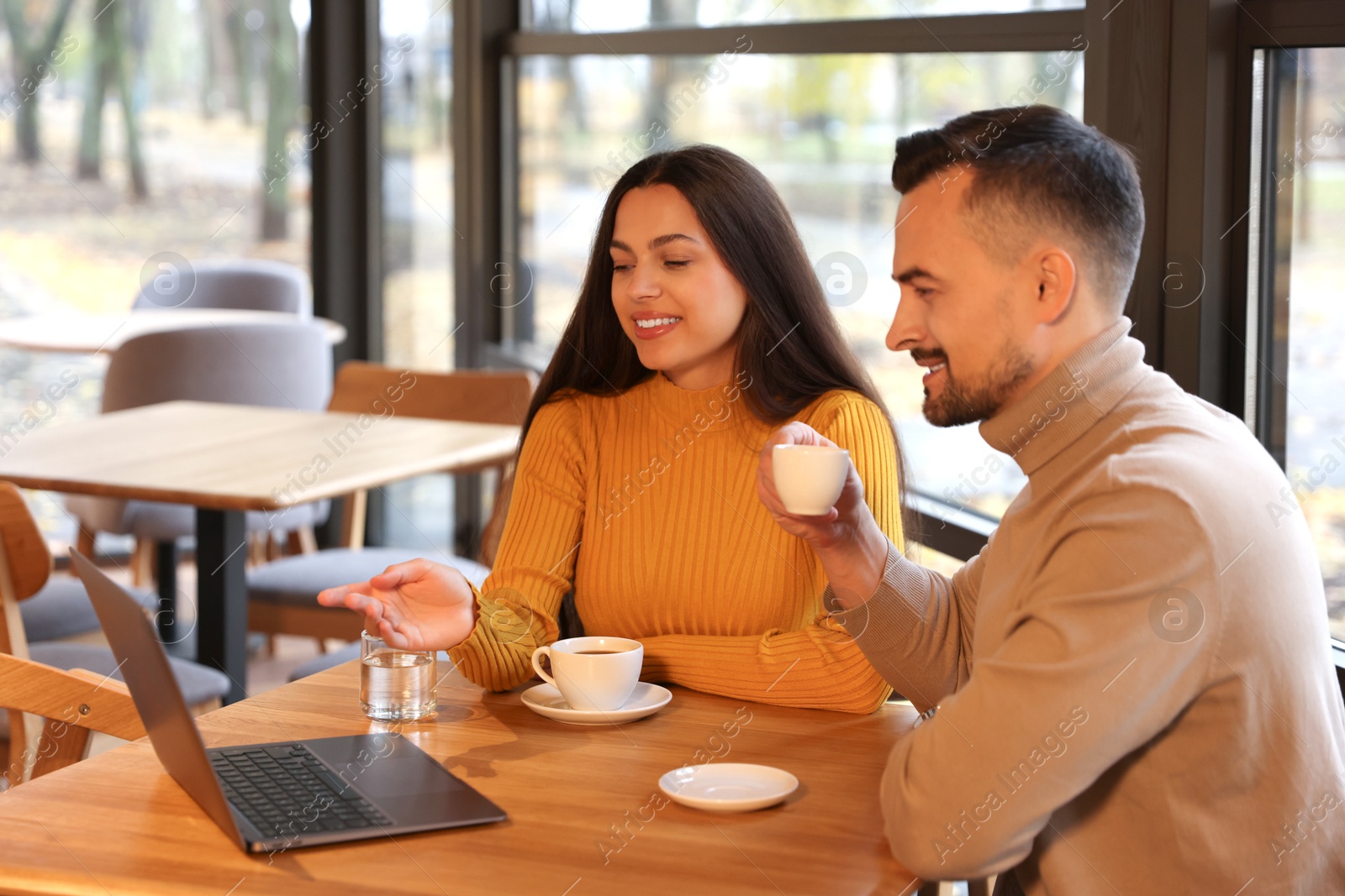 Photo of Colleagues with laptop working together at table in cafe