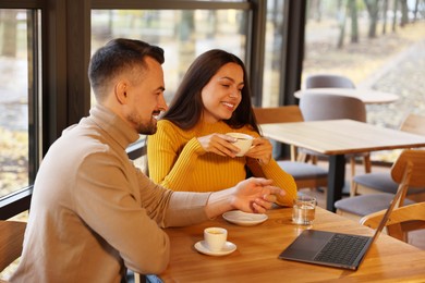 Photo of Colleagues with laptop working together at table in cafe