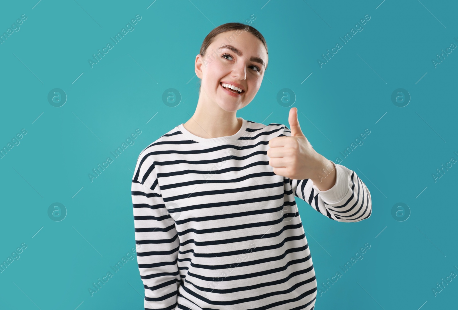 Photo of Happy woman showing thumbs up on light blue background. Like gesture