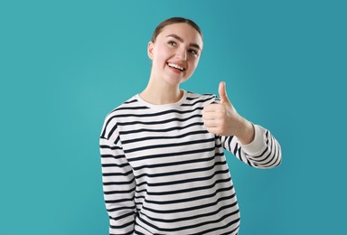 Photo of Happy woman showing thumbs up on light blue background. Like gesture