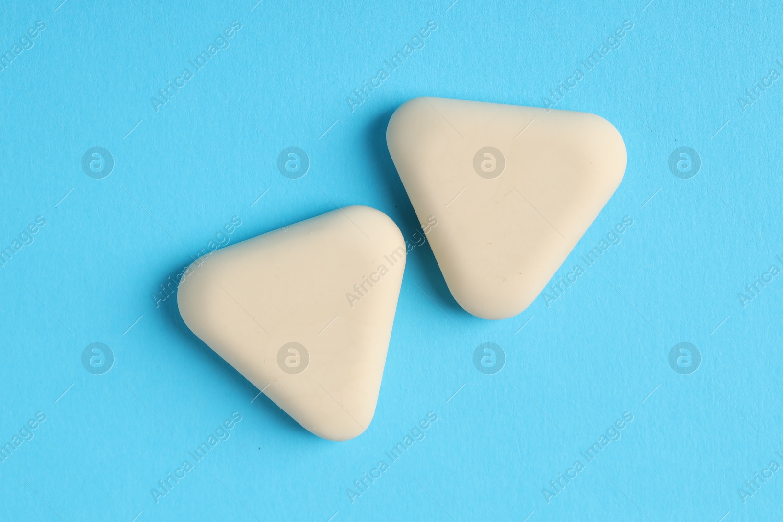 Photo of Erasers on light blue background, top view