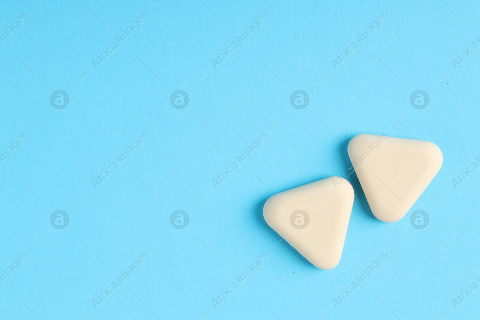 Photo of Erasers on light blue background, top view. Space for text