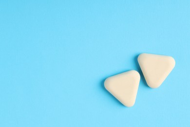 Photo of Erasers on light blue background, top view. Space for text