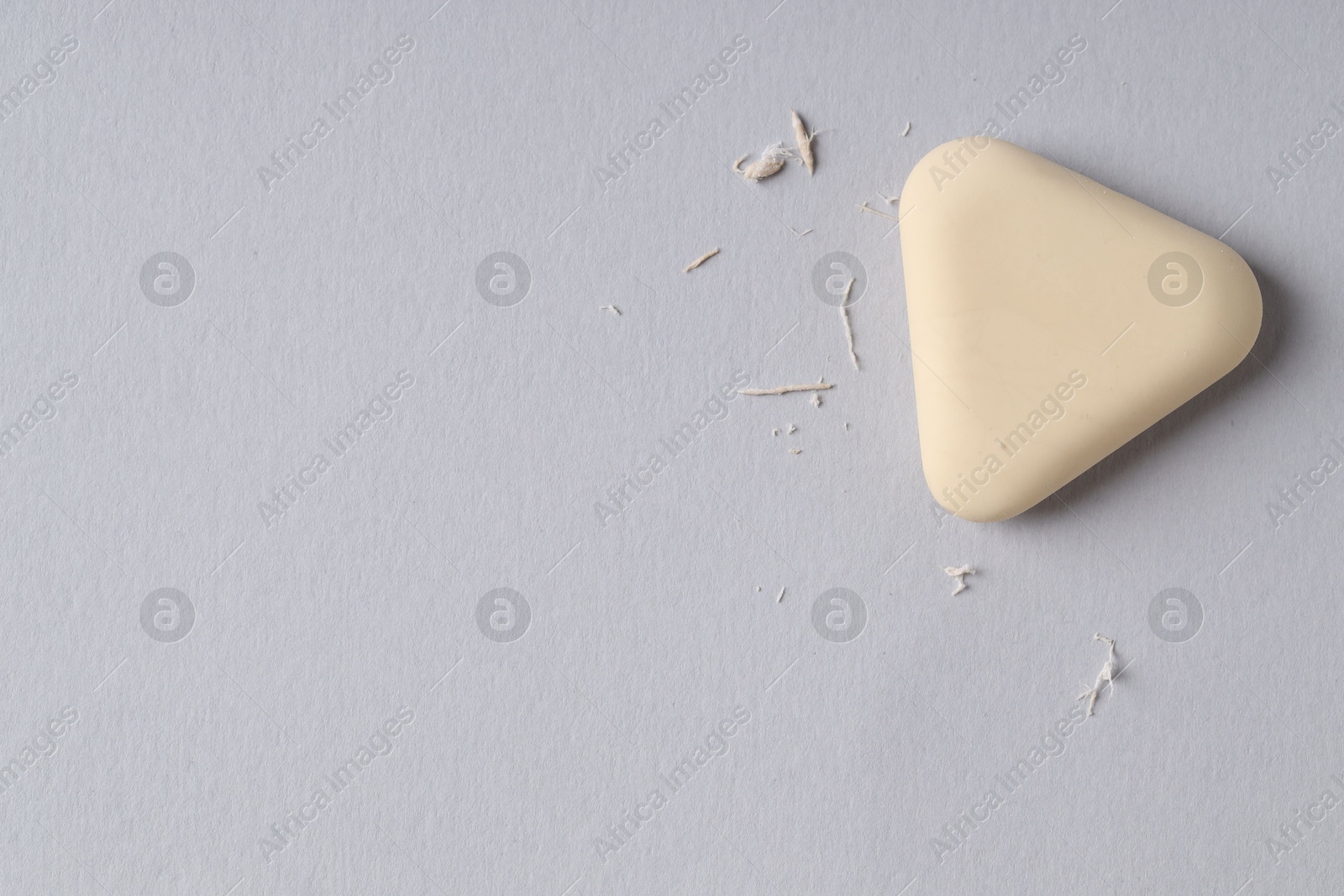 Photo of One eraser and scraps on grey background, top view. Space for text