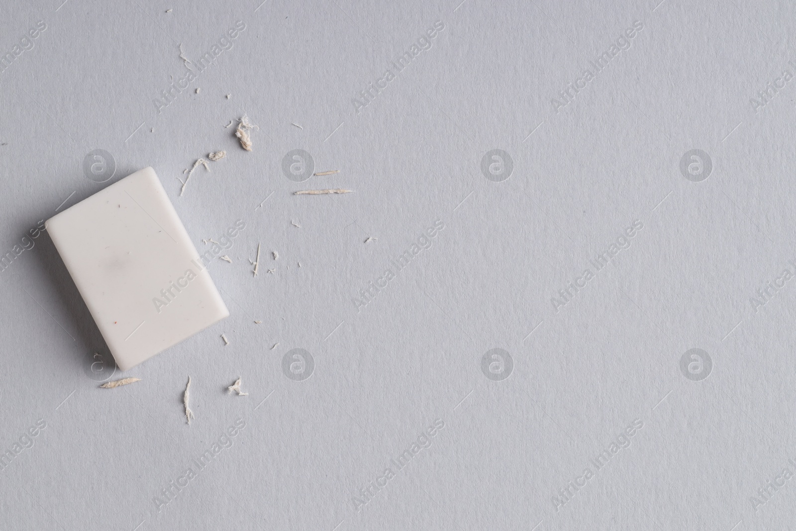 Photo of One eraser and scraps on grey background, top view. Space for text