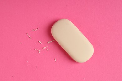 Photo of One eraser and scraps on pink background, top view