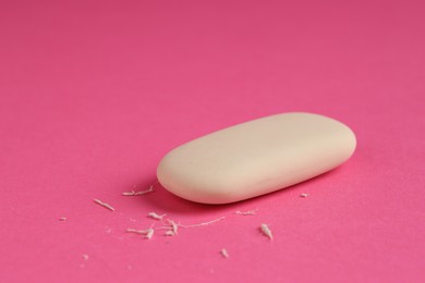 Photo of One eraser and scraps on pink background, closeup