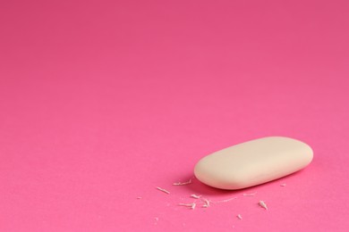 Photo of One eraser and scraps on pink background, closeup. Space for text