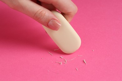 Photo of Woman using eraser on pink background, closeup