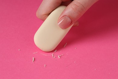 Photo of Woman using eraser on pink background, closeup